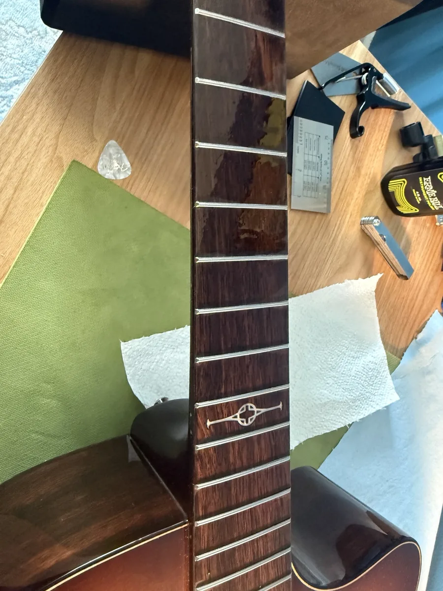Loose acoustic guitar fret being clamped and pressed back into place