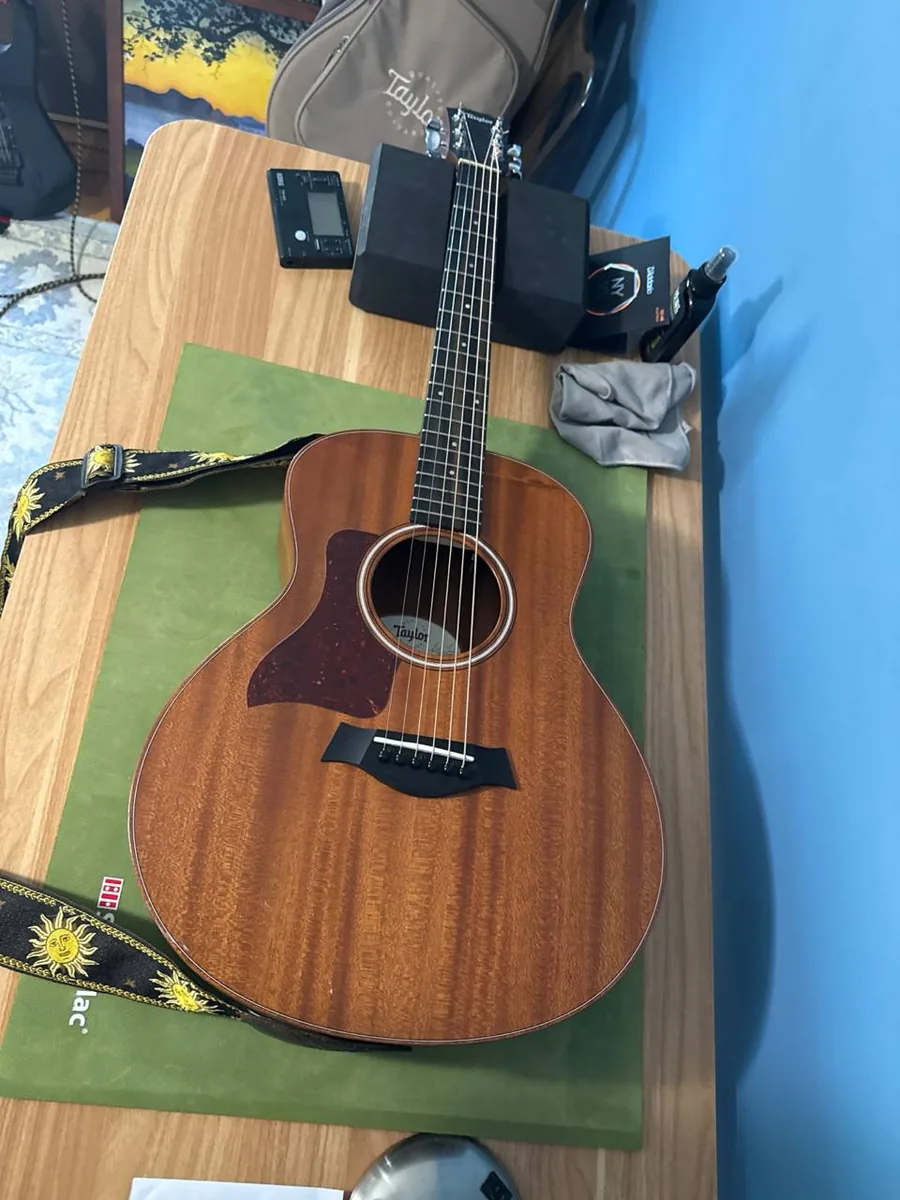 Taylor acoustic guitar used as a setup reference on the bench