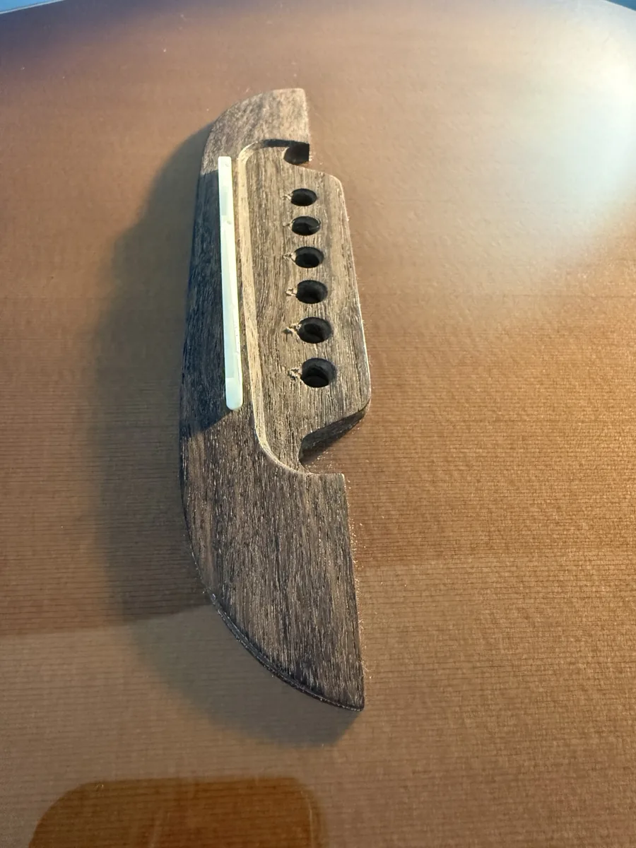 Close-up of an acoustic guitar bridge and saddle during setup work