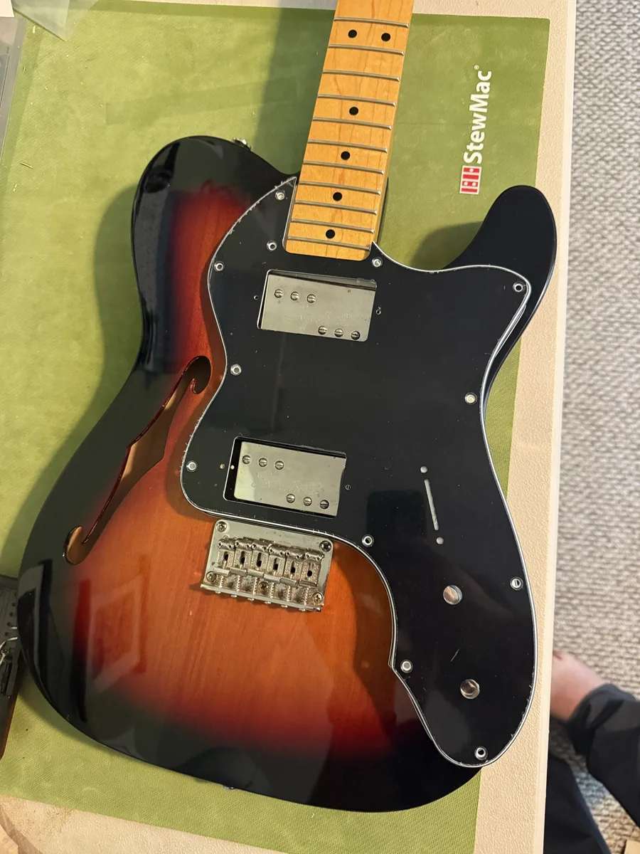 Black replacement pickguard being test-fitted around humbucker pickups