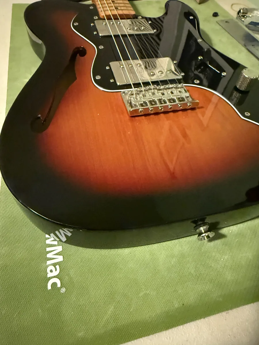 Cleaned Squier guitar with custom-fitted black pickguard after repair