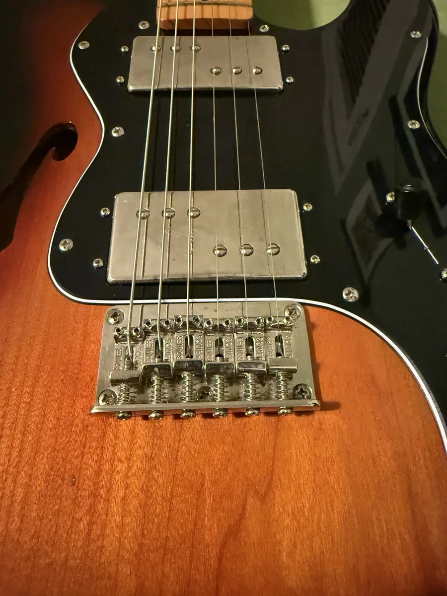Clean bridge and black pickguard on a restored Squier guitar