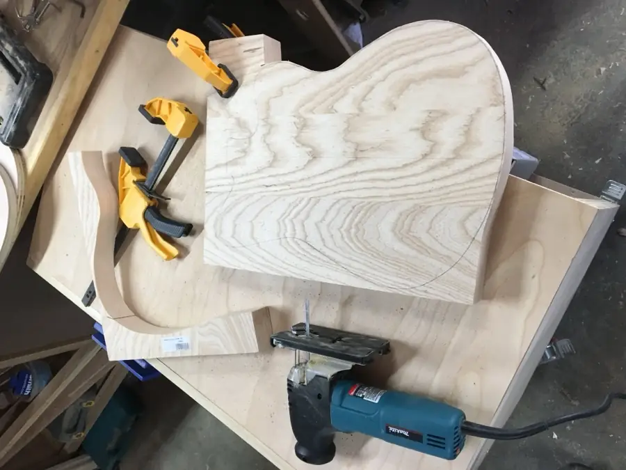 Angle grinder and clamps shaping a guitar body blank