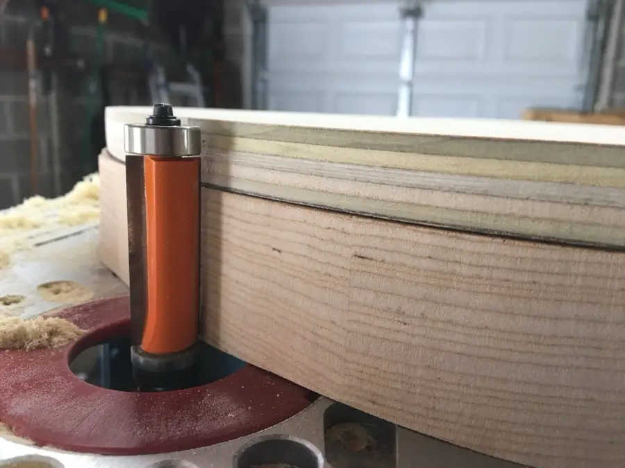 Close-up of a flush-trim router bit running the edge of a body blank